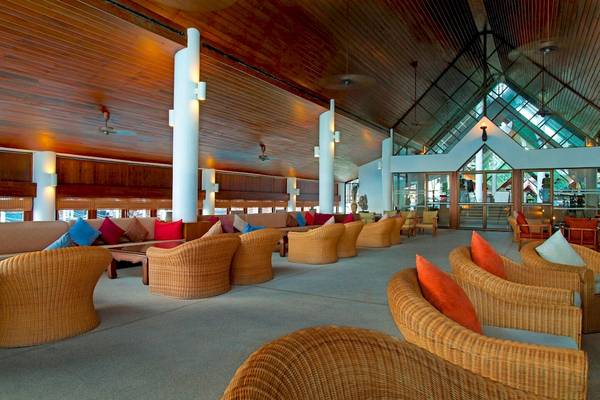 Lobby des Le Meridien Phuket Beach Resort mit Korbstühlen und Kissen.