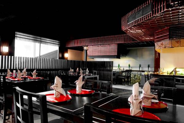 Innenraum des Restaurants im Le Meridien Phuket Beach Resort mit Tischdecken und Servietten.
