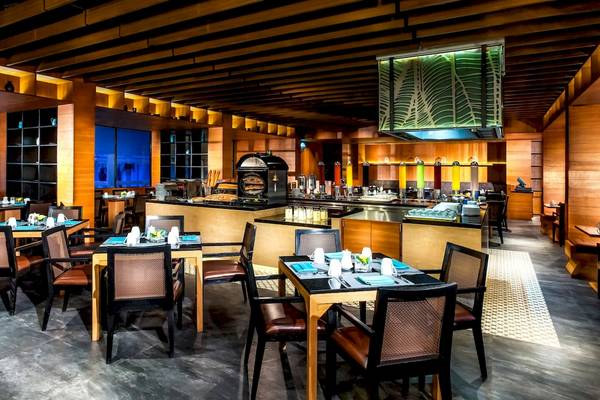 Innenansicht des Restaurants im Le Meridien Phuket Beach Resort mit Tischen, Stühlen und einer Theke.