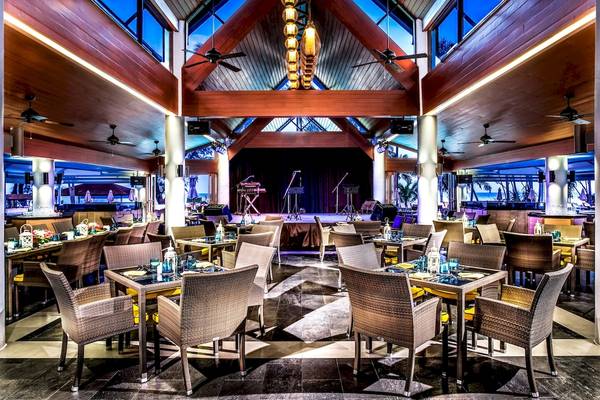 Innenbereich des Le Meridien Phuket Beach Resort mit runden Tischen, Stühlen und einer Bühne.