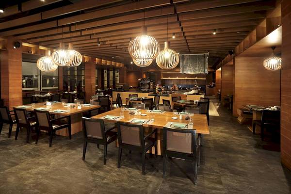 Innenbereich des Restaurants im Le Meridien Phuket Beach Resort mit Holzelementen und warmem Licht.