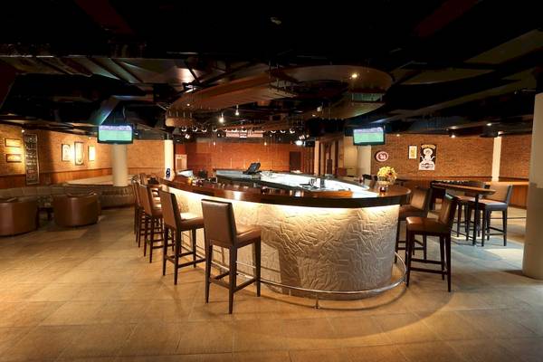 Bar im Le Meridien Phuket Beach Resort mit gepolsterten Stühlen und Fernsehern