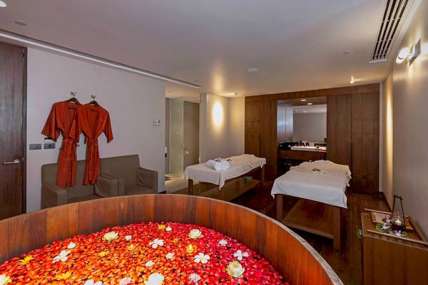 Massageraum im Le Meridien Phuket Beach Resort mit zwei Massagetischen und Blumen auf dem Boden.