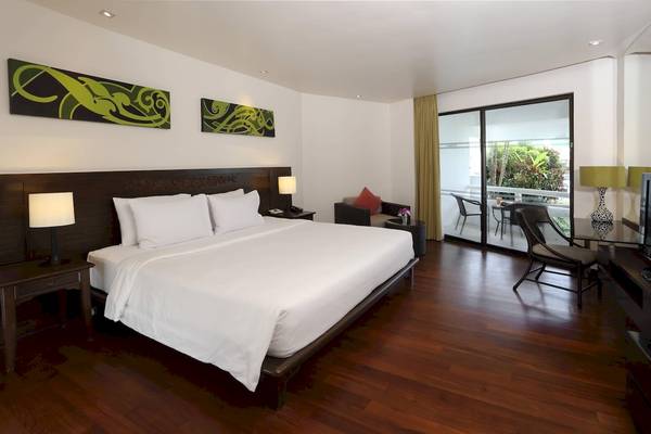 Innenansicht eines Hotelzimmers im Le Meridien Phuket Beach Resort mit Doppelbett, Wohnzimmerbereich und Balkon