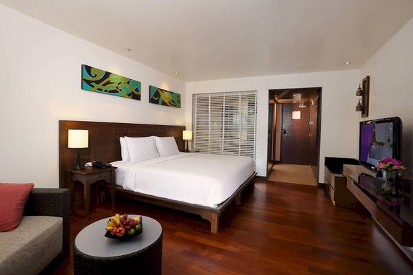 Hotelzimmer im Le Meridien Phuket Beach Resort mit Bett, Tisch, Lampe und Fernseher.