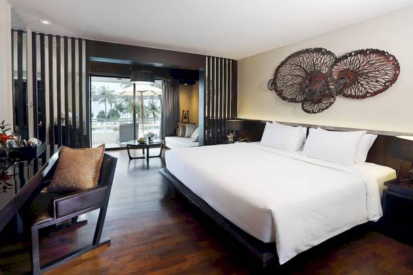 Schlafzimmer im Le Meridien Phuket Beach Resort mit Bett, Kissen, Wanddekoration und Blick auf Terrasse