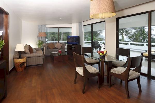 Wohnbereich des Le Meridien Phuket Beach Resort mit moderner Einrichtung und Ausblick auf Palmen.