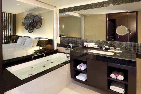 Badezimmer im Le Meridien Phuket Beach Resort mit Badewanne, Waschbecken und Spiegel.