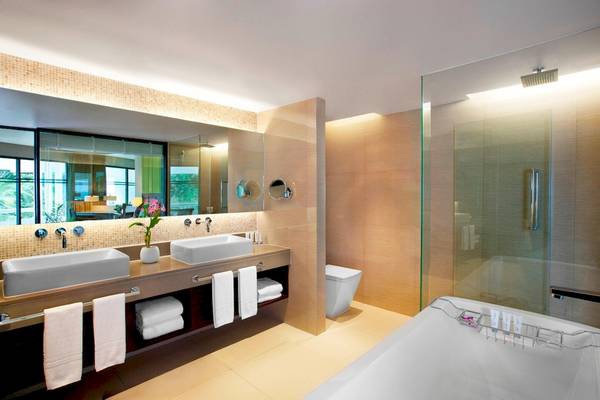 Badezimmer im Le Meridien Phuket Beach Resort mit zwei Waschbecken, Dusche und Badewanne.