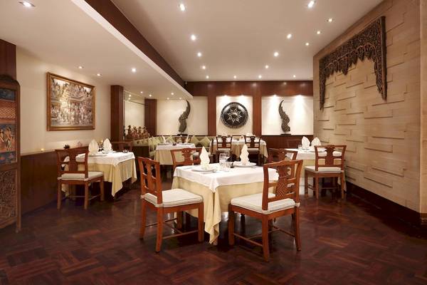 Innenbereich des Le Meridien Phuket Beach Resort mit gedeckten Tischen und dekorativen Elementen.