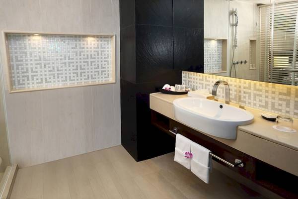 Badezimmer im Le Meridien Phuket Beach Resort mit Waschbecken, Spiegel und schwarzen Akzenten.