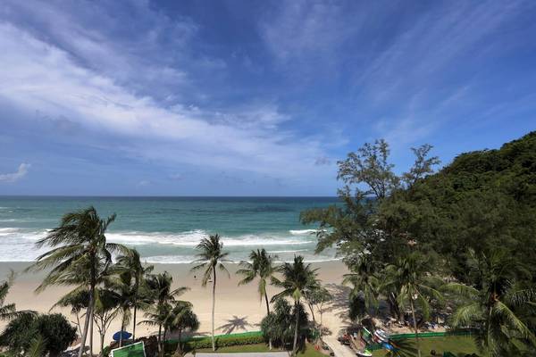 Aussicht auf den Strand des Le Meridien Phuket Beach Resorts mit Palmen und blauem Himmel