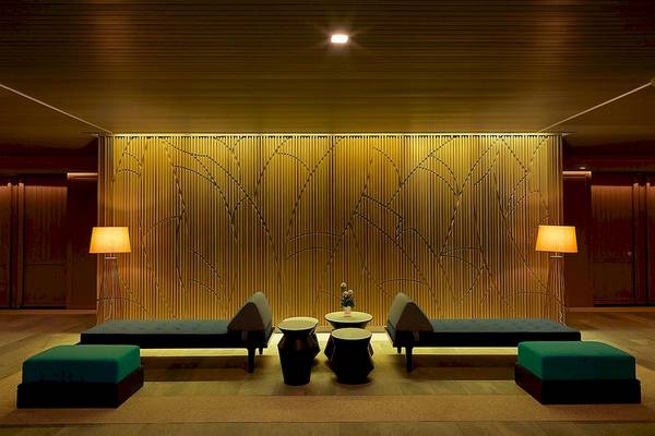 Loungebereich im Le Meridien Phuket Beach Resort mit goldener Wandverkleidung und grünen Sitzmöbeln.