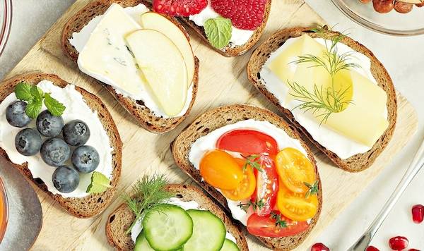 Frühstücksplatte mit Obst, Gemüse und Aufstrich auf einem Holzbrett