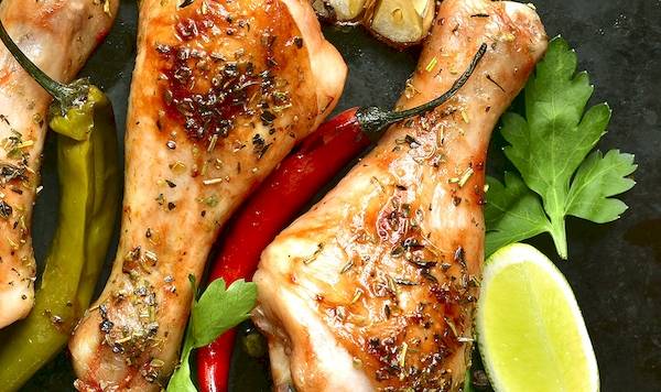 Mariniertes Hähnchen mit Gewürzen und Zitronen auf schwarzem Hintergrund.