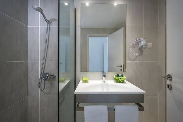 Badezimmer im Alexander House mit einer Glasdusche, einem Waschbecken und einem Haartrockner.
