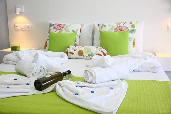 Alexander House Bett mit Handtüchern und Weinflasche auf grüner Bettwäsche