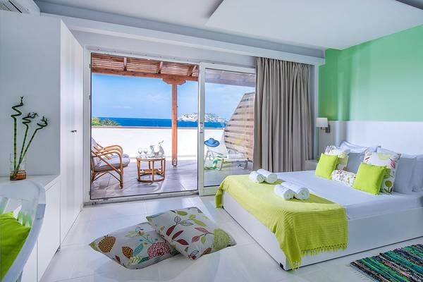 Zimmer im Alexander House Hotel mit Blick auf das Meer von einer Terrasse.