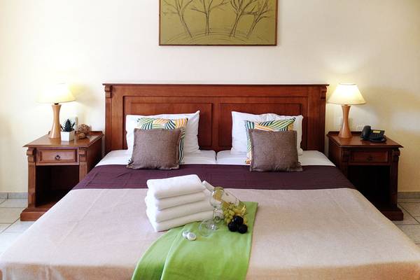Doppelbett im Zimmer des Alexander House Hotels mit Bettwäsche, Kissen, Weinflasche und Früchten