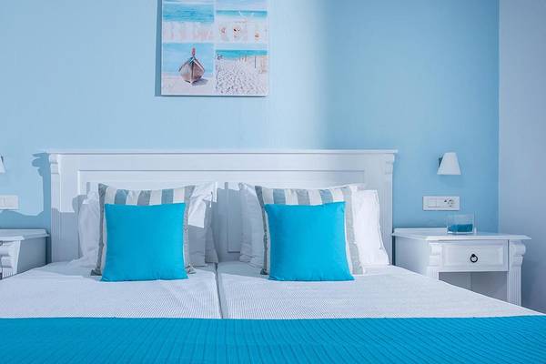 Schlafzimmer im Alexander House Hotel mit blauen Kissen und weißen Möbeln.