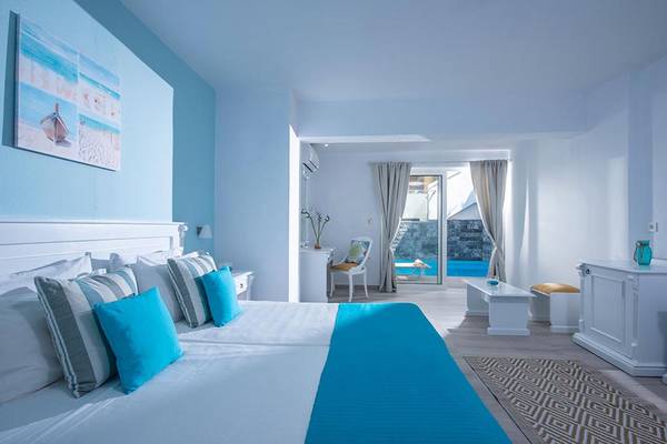 Schlafzimmer im Alexander House Hotel mit weißen und blauen Akzenten und Blick auf den Pool.