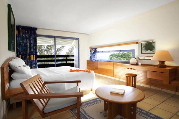 Innenansicht eines Zimmers im La Creole Beach Hotel mit Bett, Stuhl, Tisch und Aussicht