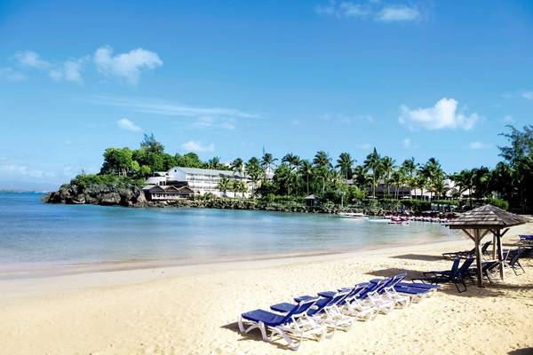 Strandszene mit Liegestühlen und Hotelgebäude am La Creole Beach Hotel & Spa