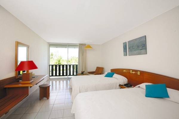 Doppelzimmer im La Creole Beach Hotel mit zwei Betten, Balkon und modernem Interieur.