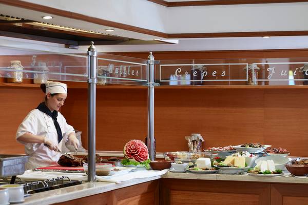 Buffettisch im Serita Beach Hotel mit verschiedenen Gerichten und einer Frau, die serviert.