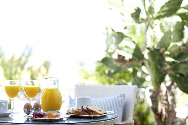 Frühstückstisch im Freien mit Orangensaft, Eiern und Brötchen im Serita Beach Hotel.