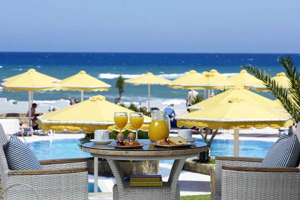 Frühstück am Pool im Serita Beach Hotel mit gelben Sonnenschirmen und Blick auf das Meer.