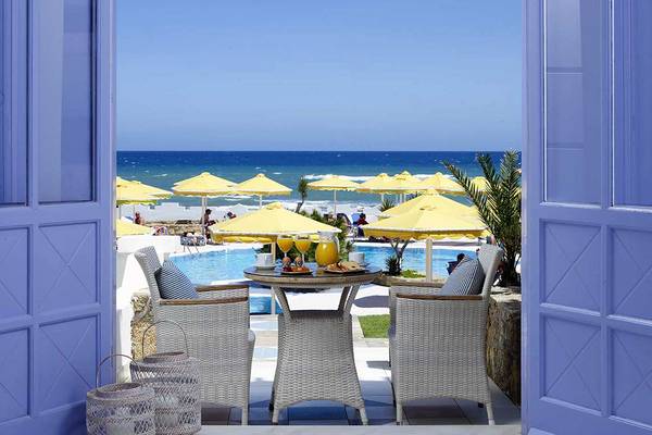 Aussicht von der Terrasse des Serita Beach Hotels auf das Meer und den Poolbereich mit gelben Sonnenschirmen.