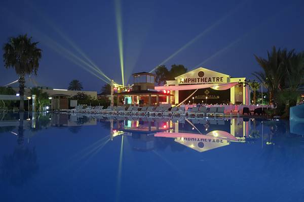 Das Amphitheater im Asteria Family Resort Side bei Nacht mit leuchtenden Palmen und einem großen Pool.