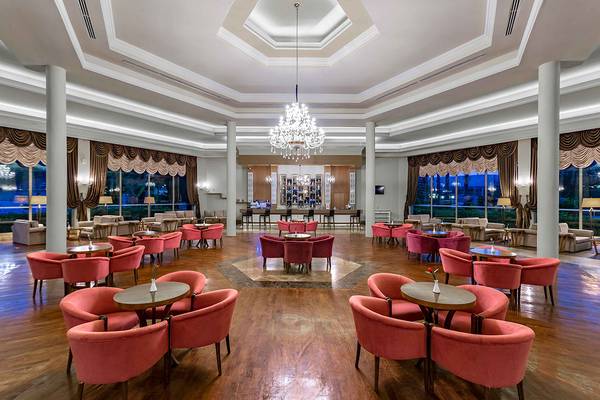 Lobby-Bereich des Asteria Family Resort Side mit einem großen Kronleuchter und vielen roten Stühlen.