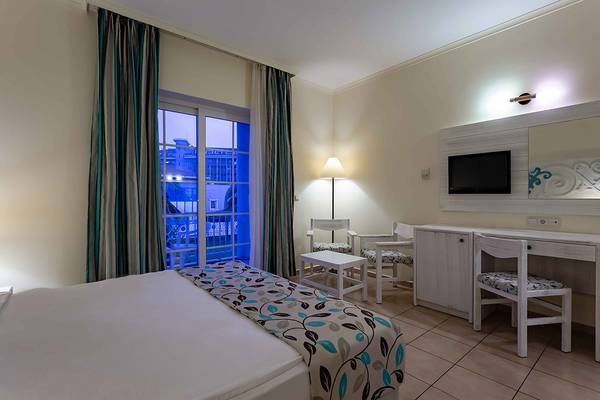 Ein ruhiges Hotelzimmer im Asteria Family Resort Side mit einem Bett, Fenstern, Möbeln und einer Aussicht auf die Stadt.