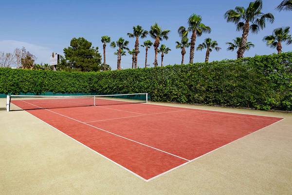 Tennisplatz im Asteria Family Resort in Side mit roten Belägen und umliegenden Palmen.