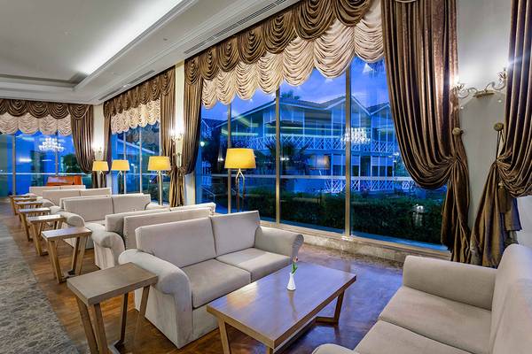 Hotellobby-Lounge mit Sofas, Couchs und Tischen vor großen Fenstern im Asteria Family Resort Side.