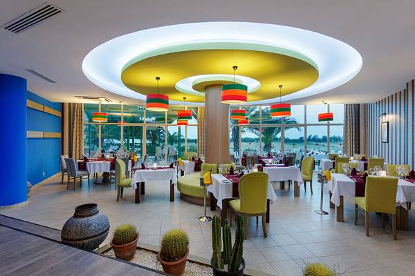 Innenansicht des Restaurants im Asteria Family Resort Side mit runden Deckenleuchten und großen Fenstern.