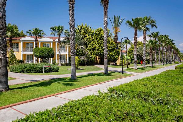Außenansicht des Asteria Family Resort in Side mit gelben Gebäuden und gepflasterten Wegen.