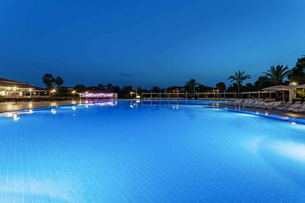 Der Swimmingpool des Asteria Family Resort Side bei Nacht, mit Loungeliegen und Beleuchtung.