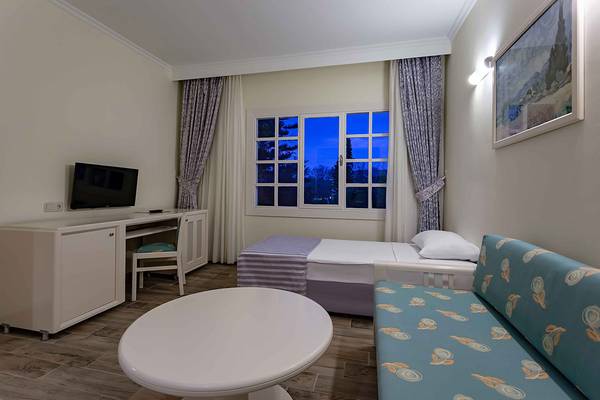 Zimmer im Asteria Family Resort Side mit Bett, Schreibtisch, Fernseher und Sofa.