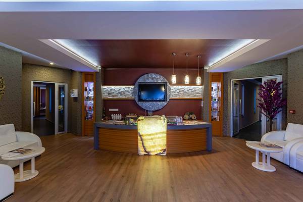 Empfangsbereich im Asteria Family Resort Side mit modernem Design, Fernseher und Marmortisch.