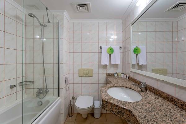 Ein Badezimmer im Asteria Family Resort Side mit Badewanne, Toilette, Waschbecken und Spiegel.