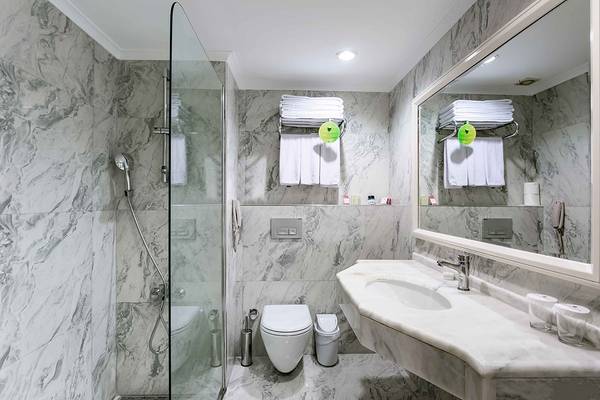 Badezimmer im Asteria Family Resort Side mit Marmorwänden, Duschkabine und Waschbecken.