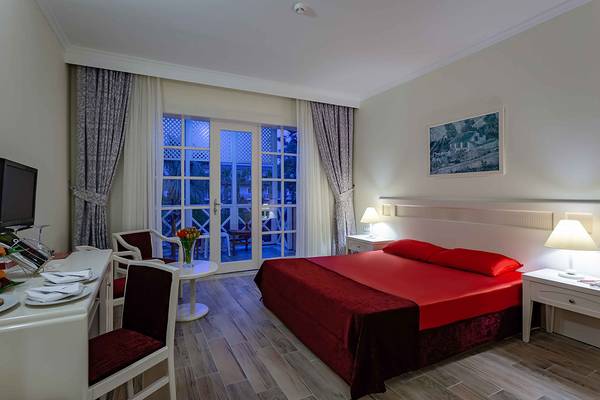Hotelzimmer im Asteria Family Resort Side mit einem roten Bett, Schreibtisch und Balkon.