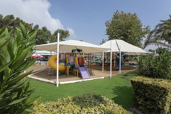 Kinderspielplatz mit gelbem Spielturm und Rutsche unter weißen Dächern