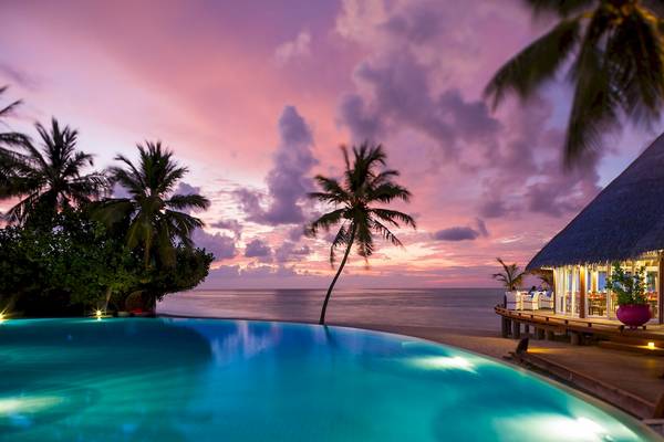 Sonnenuntergang am Strand mit dem Sun Siyam Vilu Reef Hotel und einem Swimmingpool