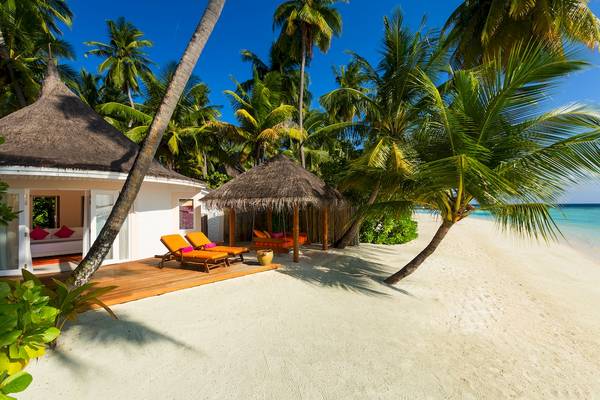 Hütte am Strand des Sun Siyam Vilu Reef Hotels mit Liegen und Palmen
