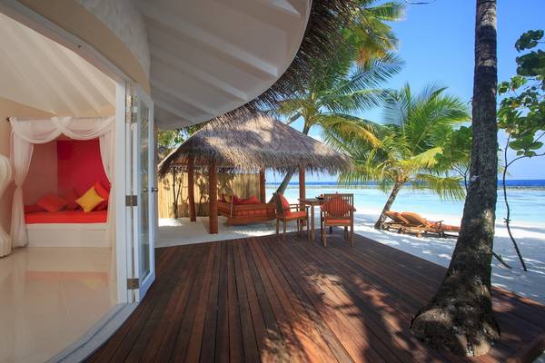 Terrasse im Sun Siyam Vilu Reef Hotel mit Blick auf eine gemütliche Hängematte und Strandliegen.