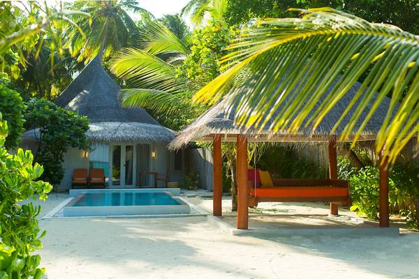Außenbereich des Sun Siyam Vilu Reef Hotels mit Swimmingpool und Hütten.